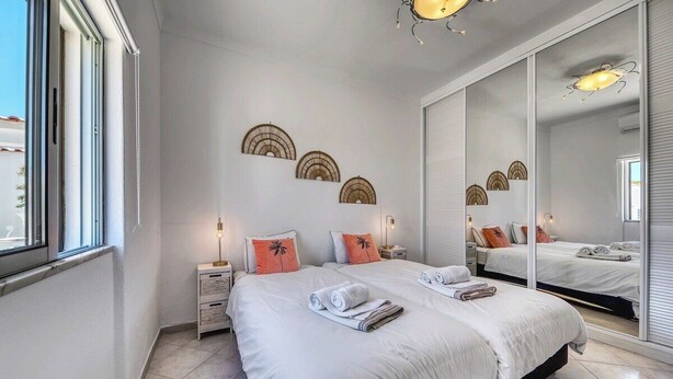 Ein Schlafzimmer mit einem großen Bett, zwei Nachttischen, einem Spiegel und Wanddekoration.