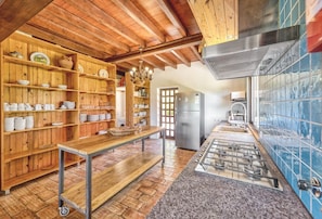 A rustic kitchen with wooden shelves, a central island, and a tiled backsplash. - Villa Fuzeiros - Amazing villa in a green valley! (São Bartolomeu de Messines)