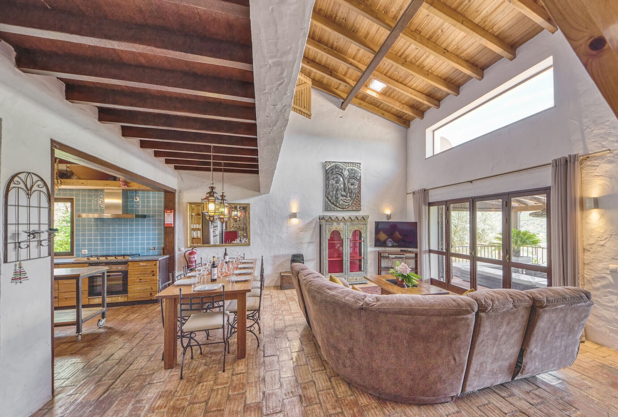 A spacious living area with a wooden ceiling, a dining table, and a comfortable seating area.
