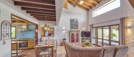 A spacious living area with a wooden ceiling, a dining table, and a comfortable seating area.