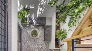 Un espace extérieur moderne agrémenté de carreaux décoratifs, d’une plante en pot et de plantes grimpantes.