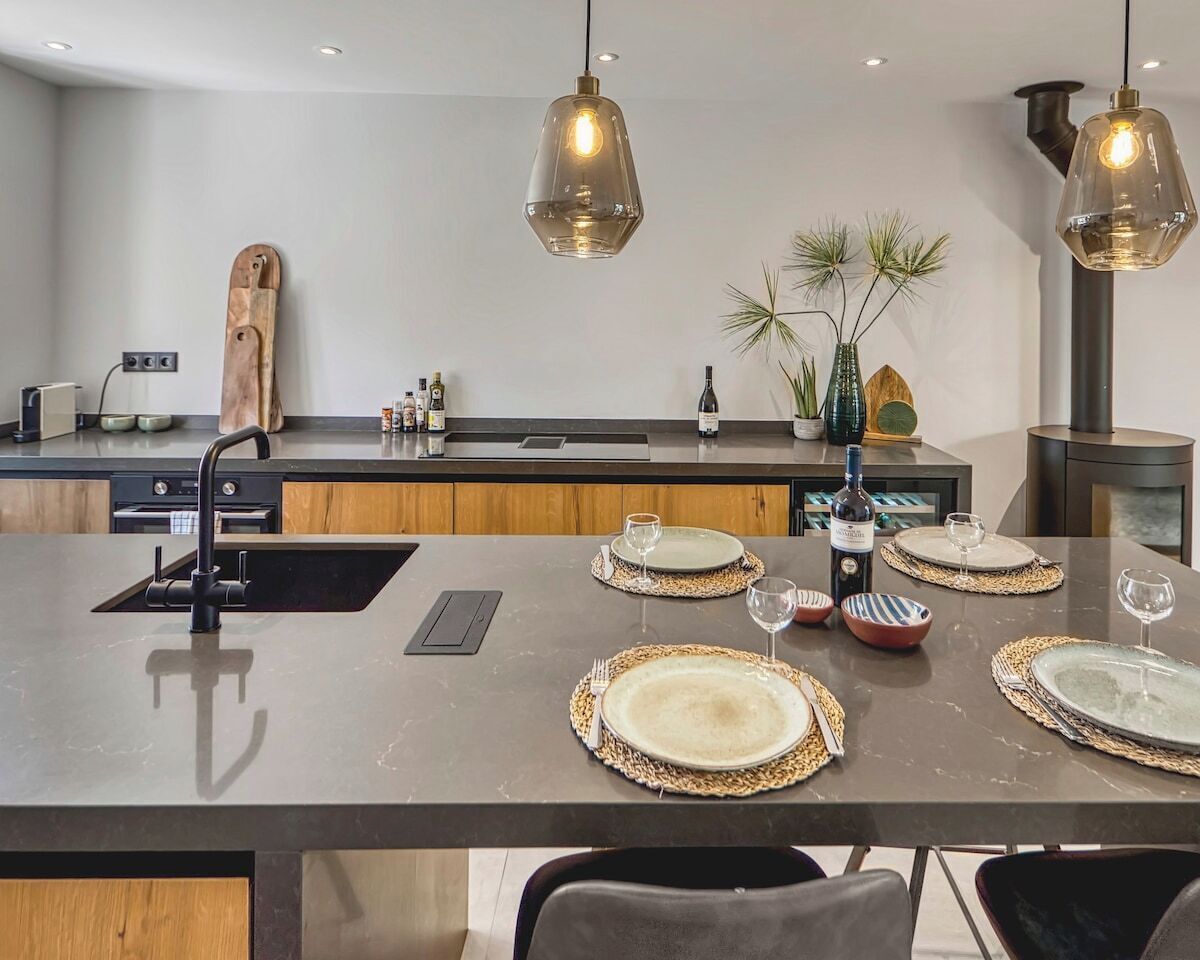 A modern kitchen with a central island, pendant lighting, and a variety of kitchen appliances.