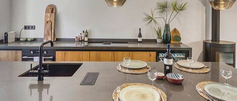 A modern kitchen with a central island, pendant lighting, and a variety of kitchen appliances.