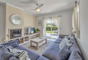 A living room with a sofa, TV, and a ceiling fan. - Casa Bougainvilla - Lovely Villa walking distance to Carvoeiro (Carvoeiro)