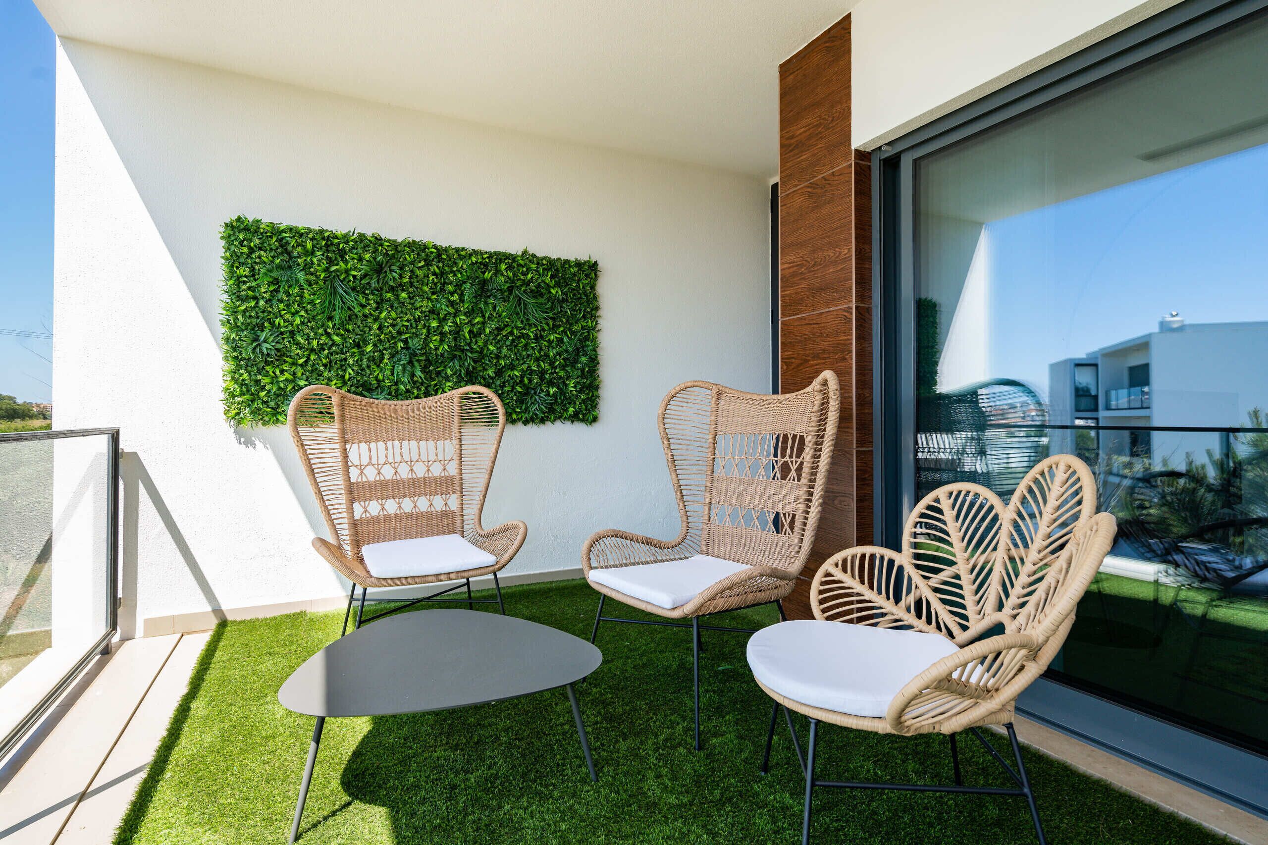 A balcony with wicker chairs, a small table, and a green wall.