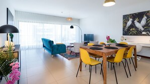 Una sala de estar moderna con comedor, que incluye un sofá azul, sillas amarillas y una mesa de comedor de madera.
