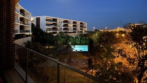 Un hotel de varios pisos con balcones, una piscina y vistas del paisaje circundante.