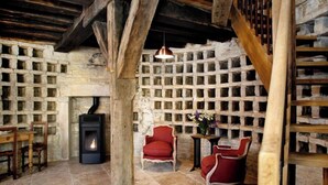 A rustic room with a stone wall, a fireplace, and wooden furniture. - Studio Michel (Pichanges)
