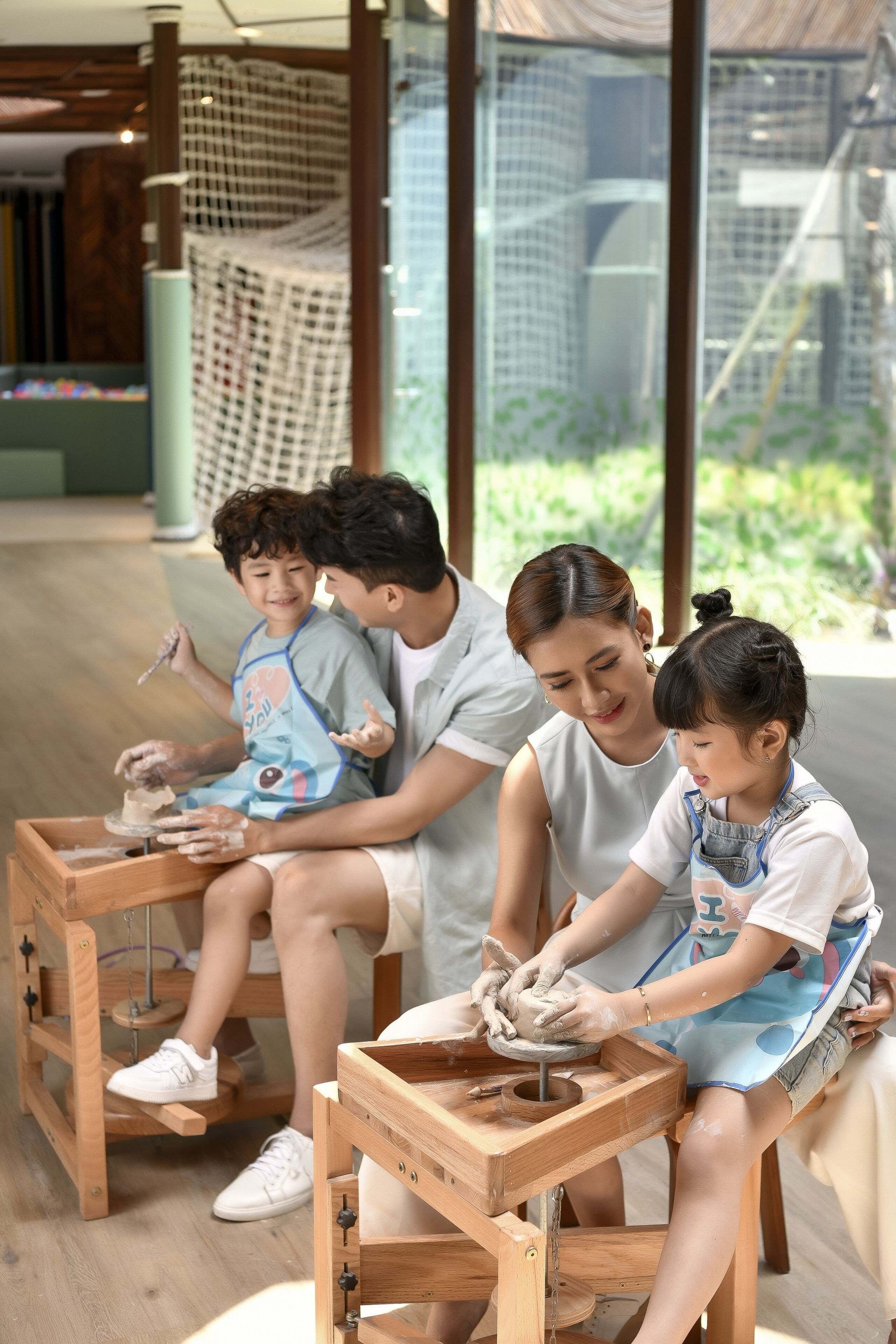 A group of people engaged in pottery making at a wooden table with a pottery wheel.