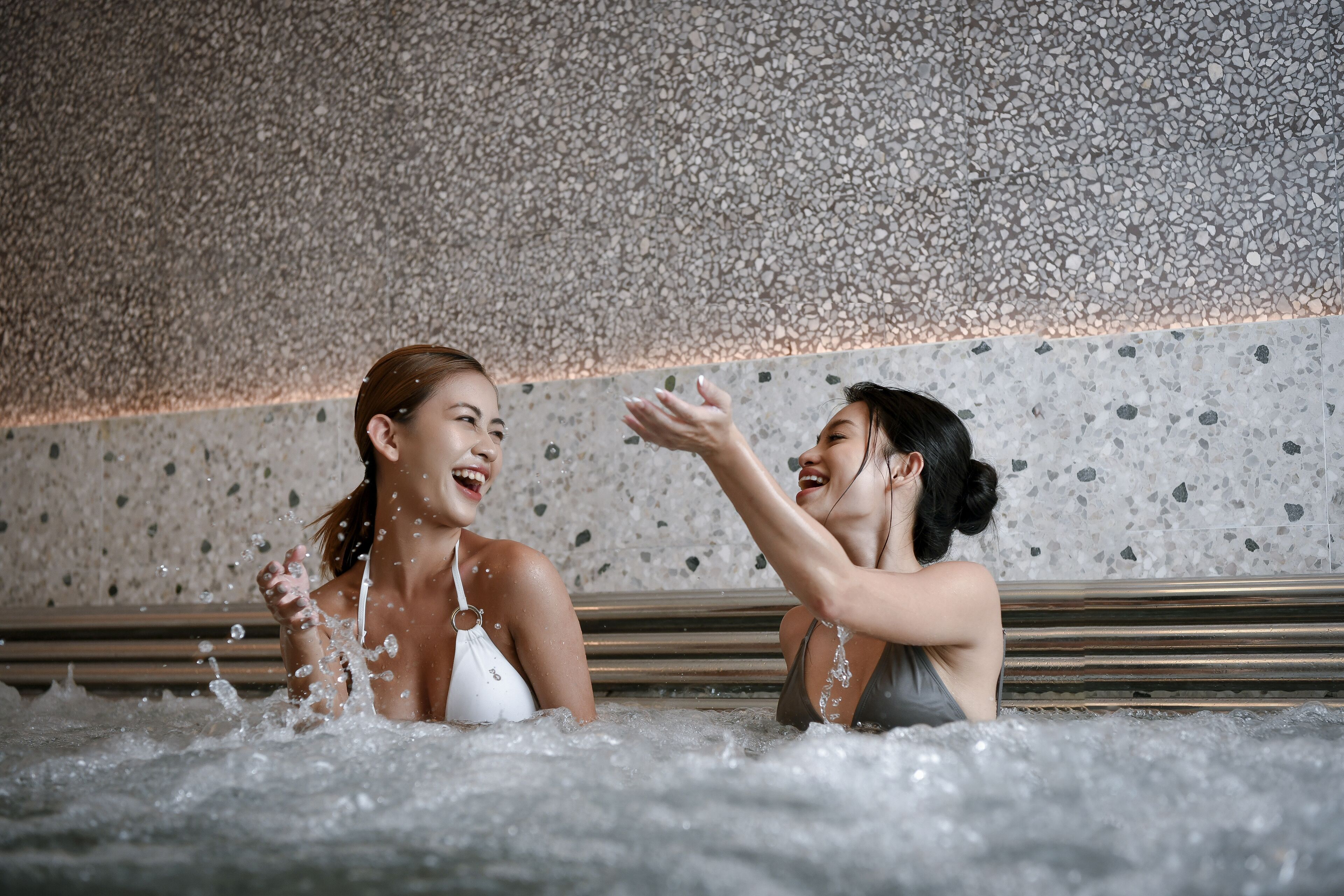 Deux personnes dans un bain à remous, avec un mur dont la texture rappelle celle de petits galets.