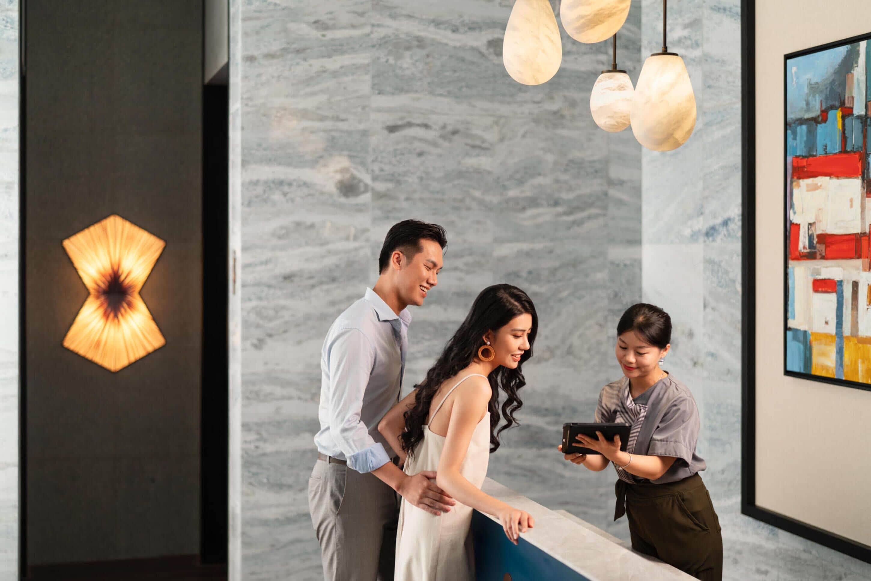 A reception area with a marble wall, pendant lighting, and a framed abstract painting.
