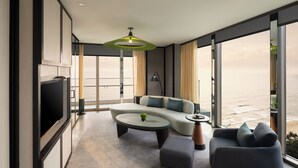 A modern living room with a large window, a sofa, a coffee table, and a TV. - New World Hoiana Beach Resort (Da Nang)