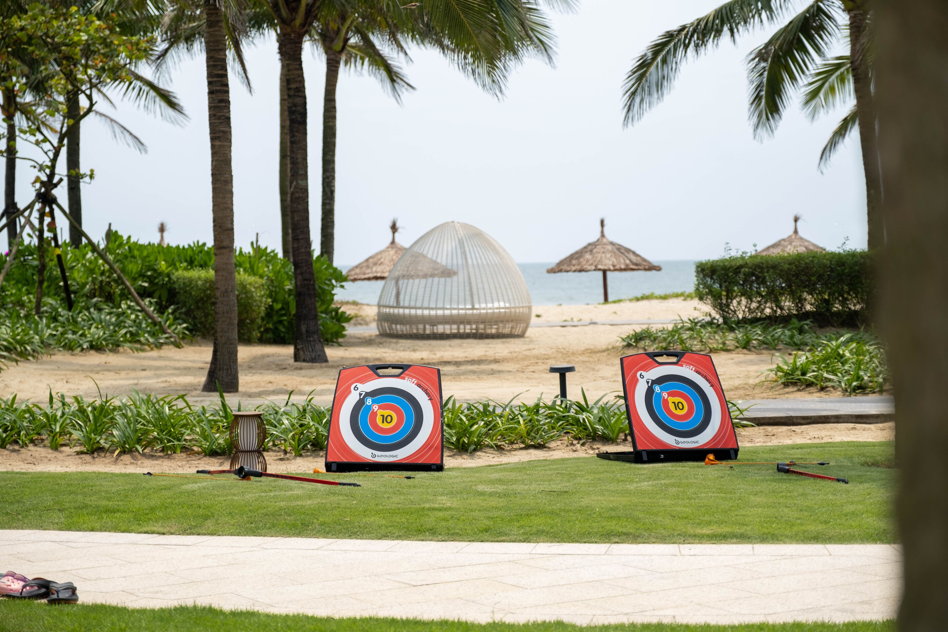 A golf course with two targets, palm trees, and a beach in the background.