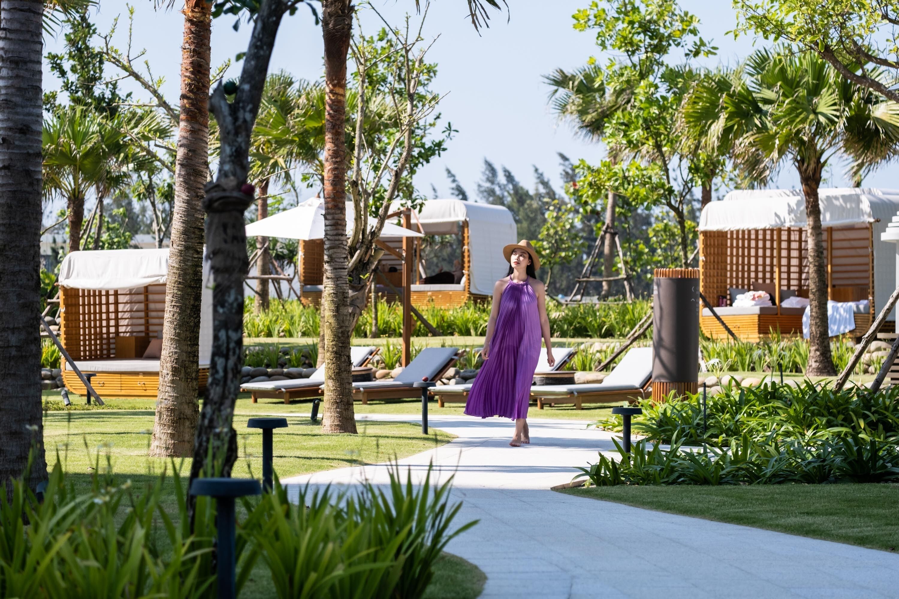 A resort with outdoor seating, palm trees, and a pathway.