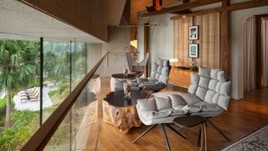 A modern living room with a glass wall, a hanging chair, a sofa, and a wooden coffee table. - New World Hoiana Beach Resort (Da Nang)