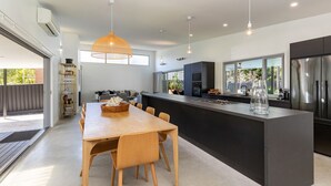 A modern kitchen with a central island, pendant lighting, and a view of the outdoors. - Stunning, Sleek and Refined, The Black Beach House is perfection from the time you walk through the (Elizabeth Beach)
