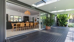 A modern kitchen with a dining area, large windows, and a potted plant. - Stunning, Sleek and Refined, The Black Beach House is perfection from the time you walk through the (Elizabeth Beach)