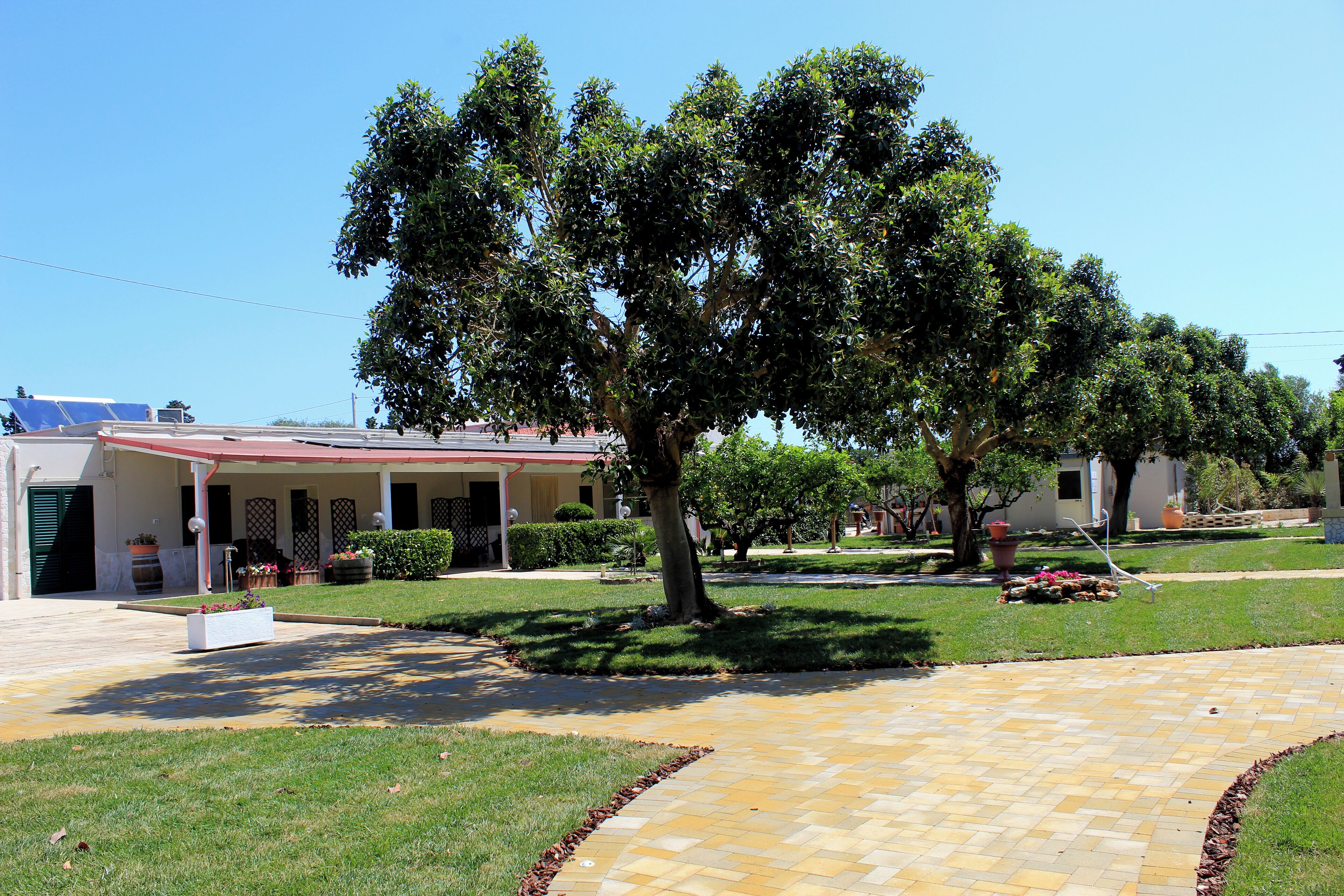 A residential area with a paved driveway leading to a house with a red roof and a covered porch.
