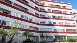 Un immeuble à plusieurs étages, doté d’une façade rouge et blanche, sur lequel on peut lire l’inscription « MIRA ROCHA ».