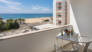 Un balcon avec une table, des chaises et une vue sur la plage et l’océan.