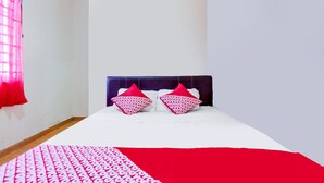 A bedroom with a bed, two pillows, a red and white blanket, and a window with red curtains. - Hotel O Wisma Heksa (Batam)
