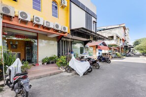 A street view with a yellow building housing a shop named "HERSA 1" and a restaurant. - Hotel O Wisma Heksa (Batam)