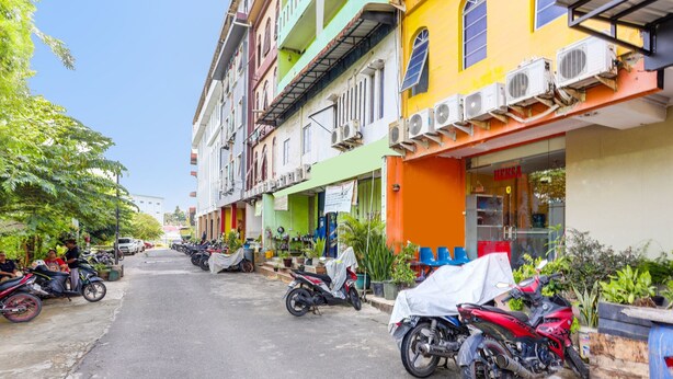 A street lined with colorful buildings, parked motorcycles, and a clear sky. - Hotel O Wisma Heksa (Batam)