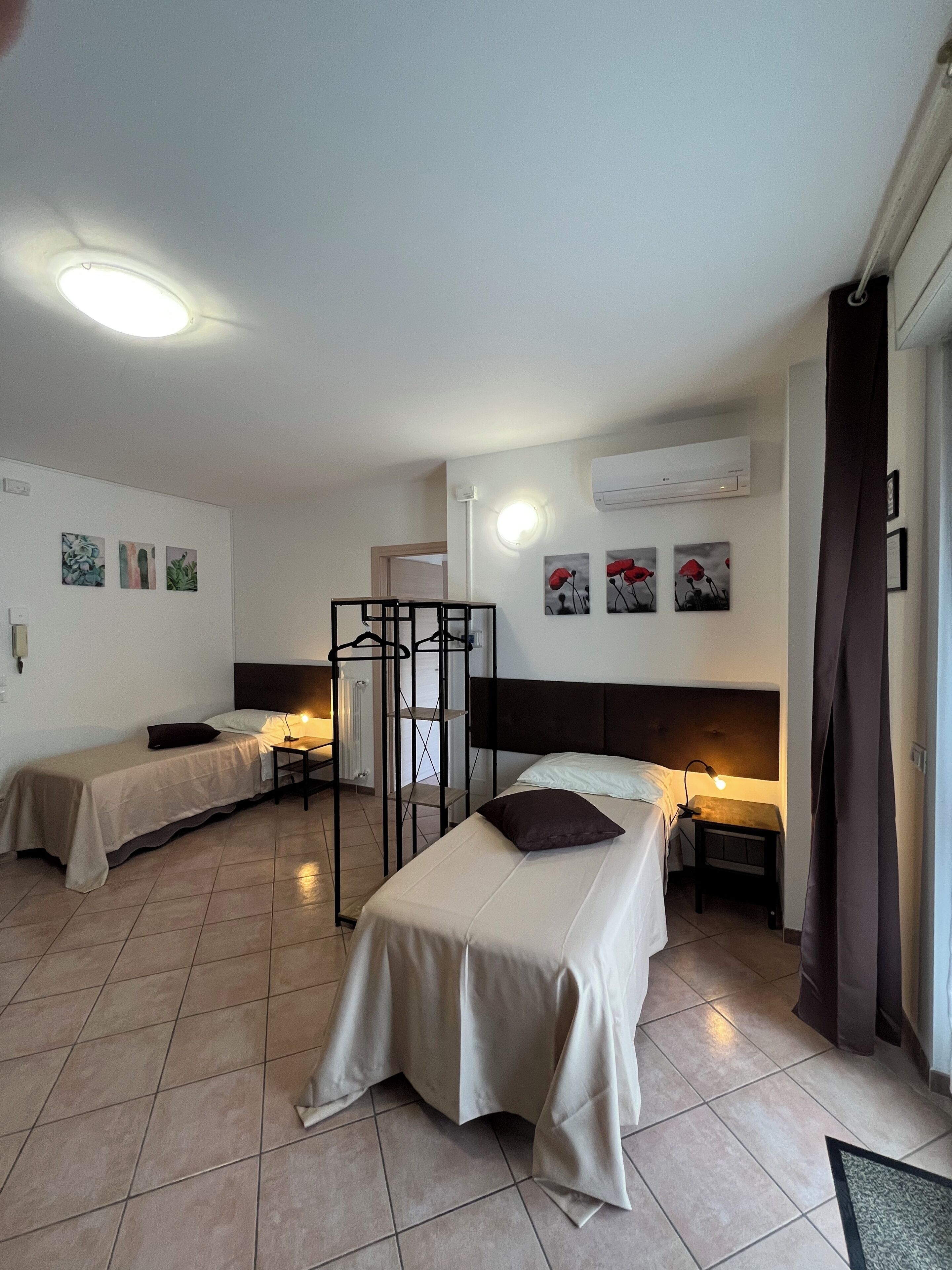 A hotel room with two beds, a standing lamp, and artwork on the walls.