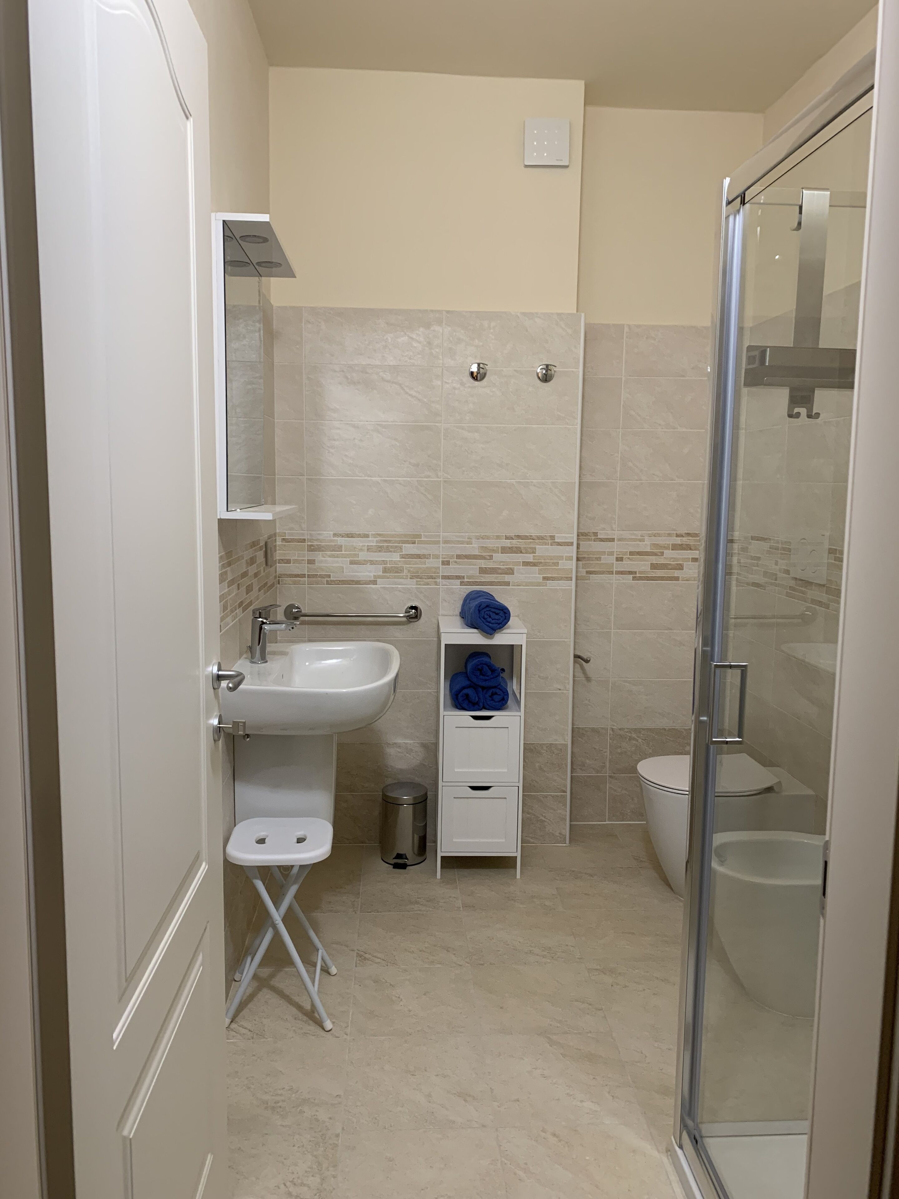 Un baño moderno con cabina de ducha de vidrio, un lavabo blanco y un inodoro.