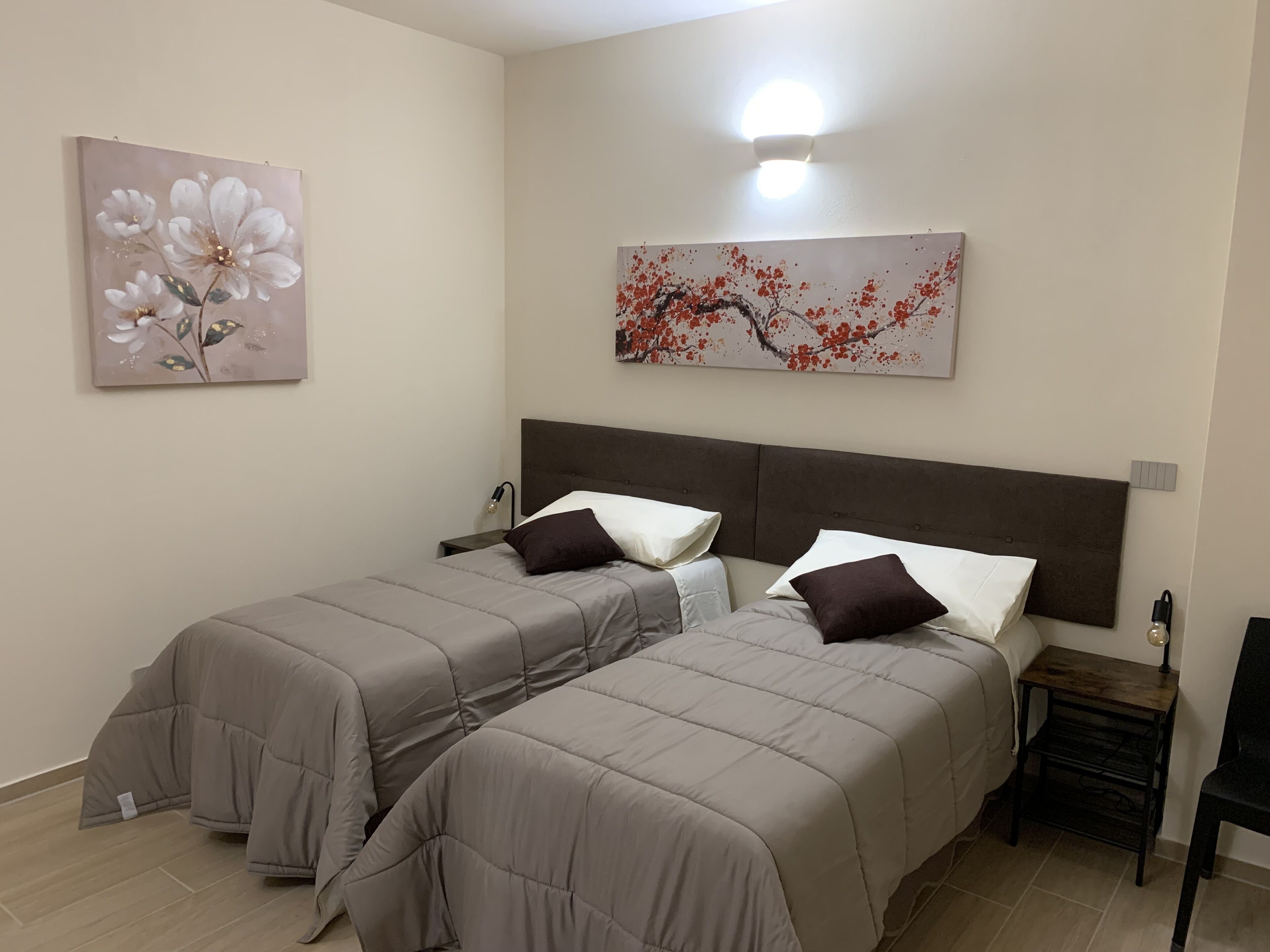 Un dormitorio con dos camas, una mesita de noche y decoración en la pared.