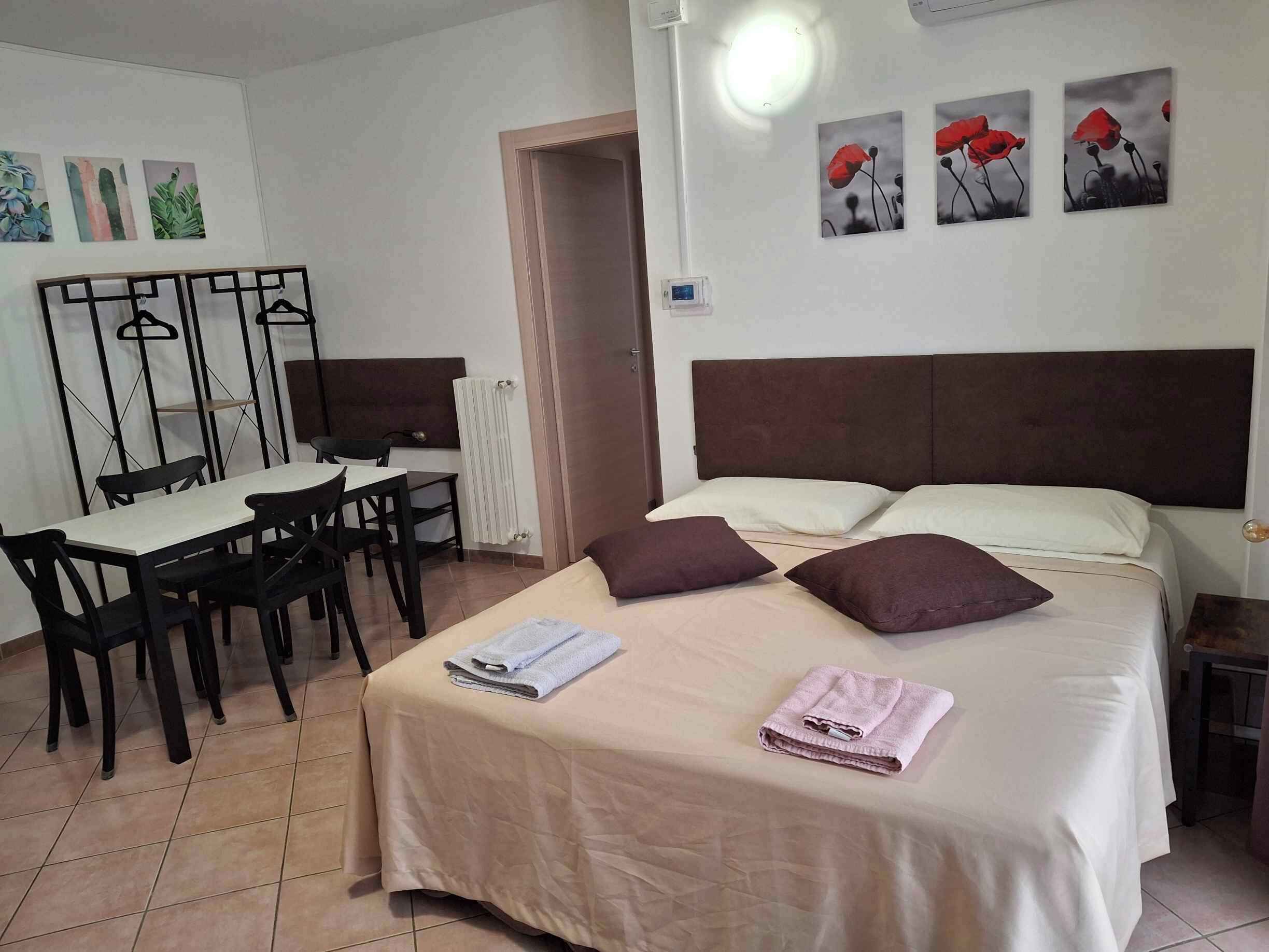 A hotel room with a bed, two pillows, a table with chairs, a desk, and a mirror.