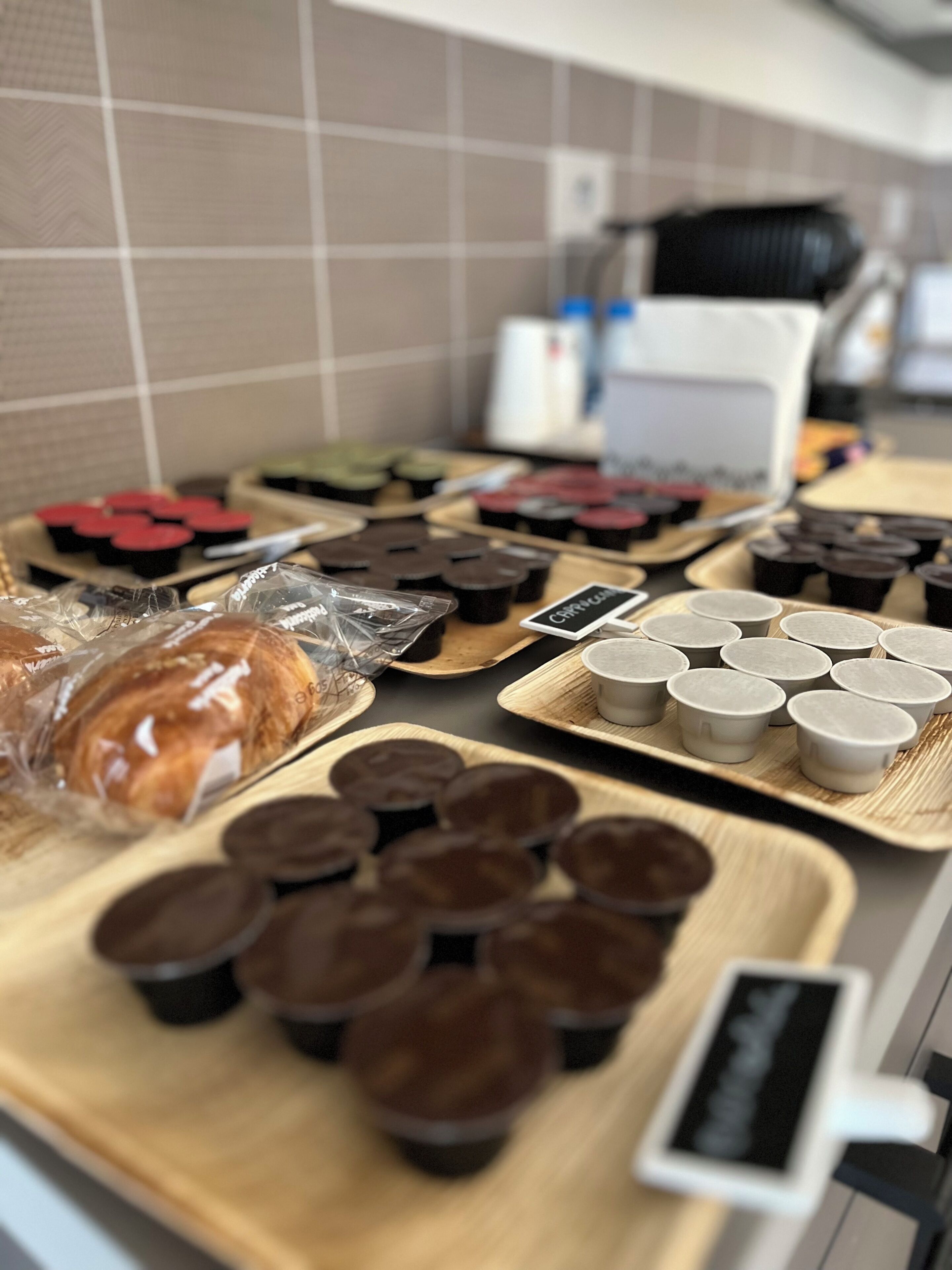 A kitchen counter with various food items and containers, including pastries, chocolate cups, and a coffee machine.