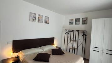 Un dormitori amb llit, taules de nit, armari i obra d'art a la paret.