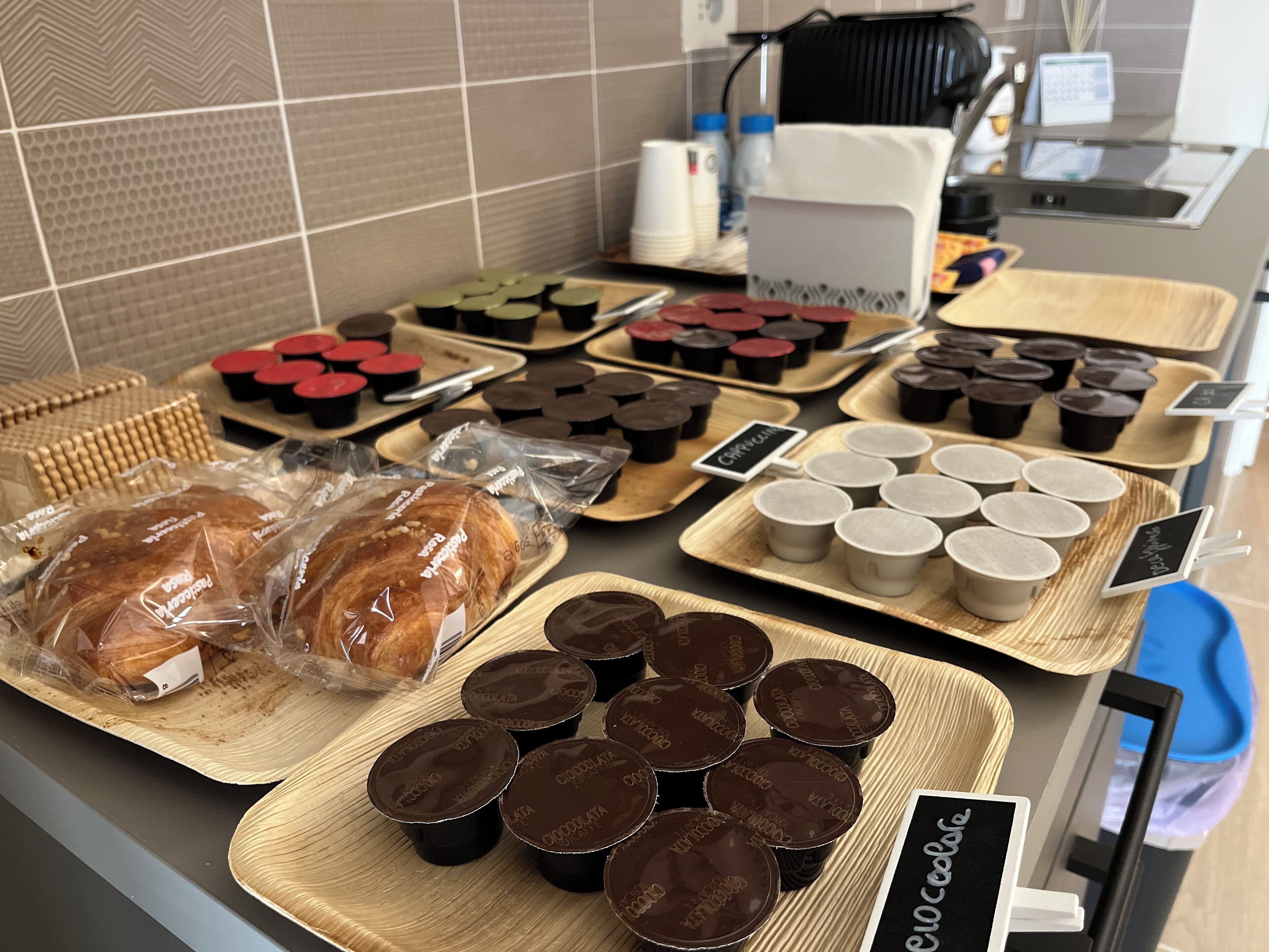 Mostrador de panadería con diversos productos horneados y vasitos de chocolate.