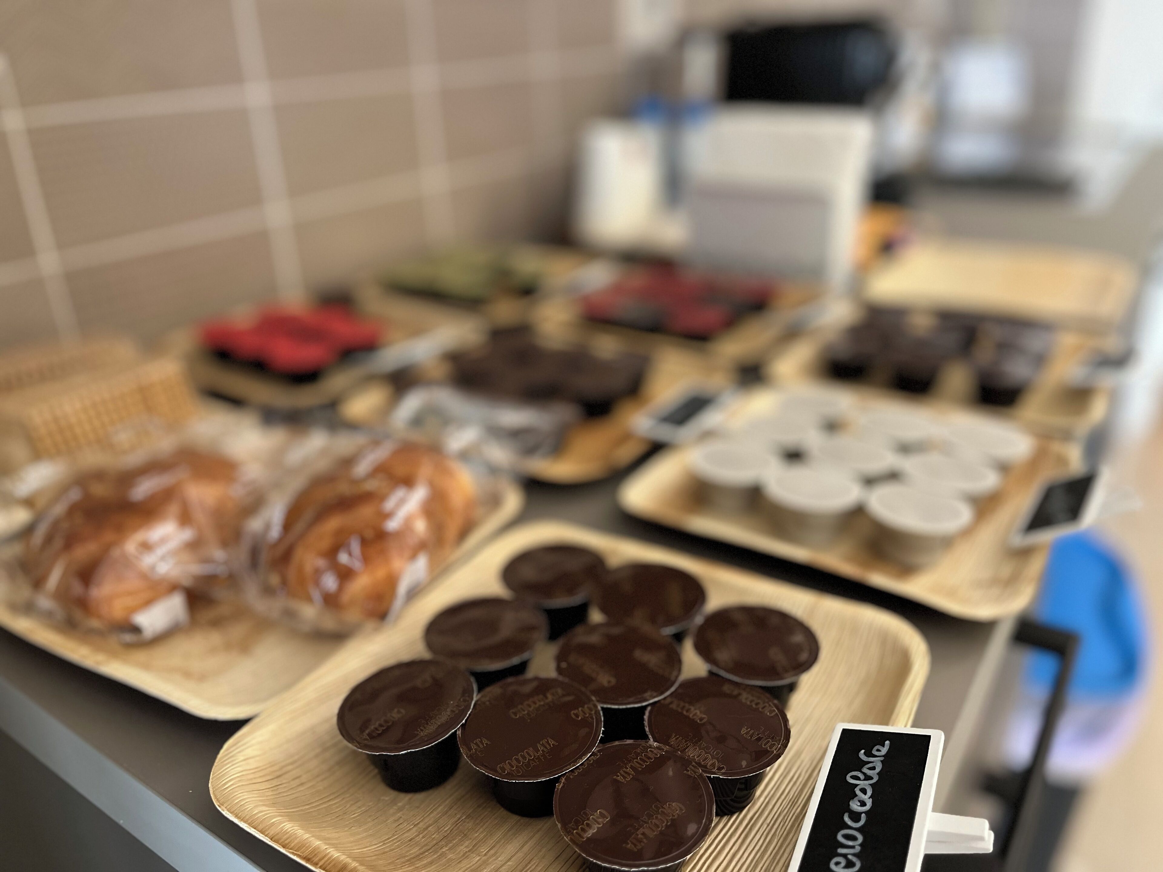 A display of food items including pastries and chocolate cups on trays.