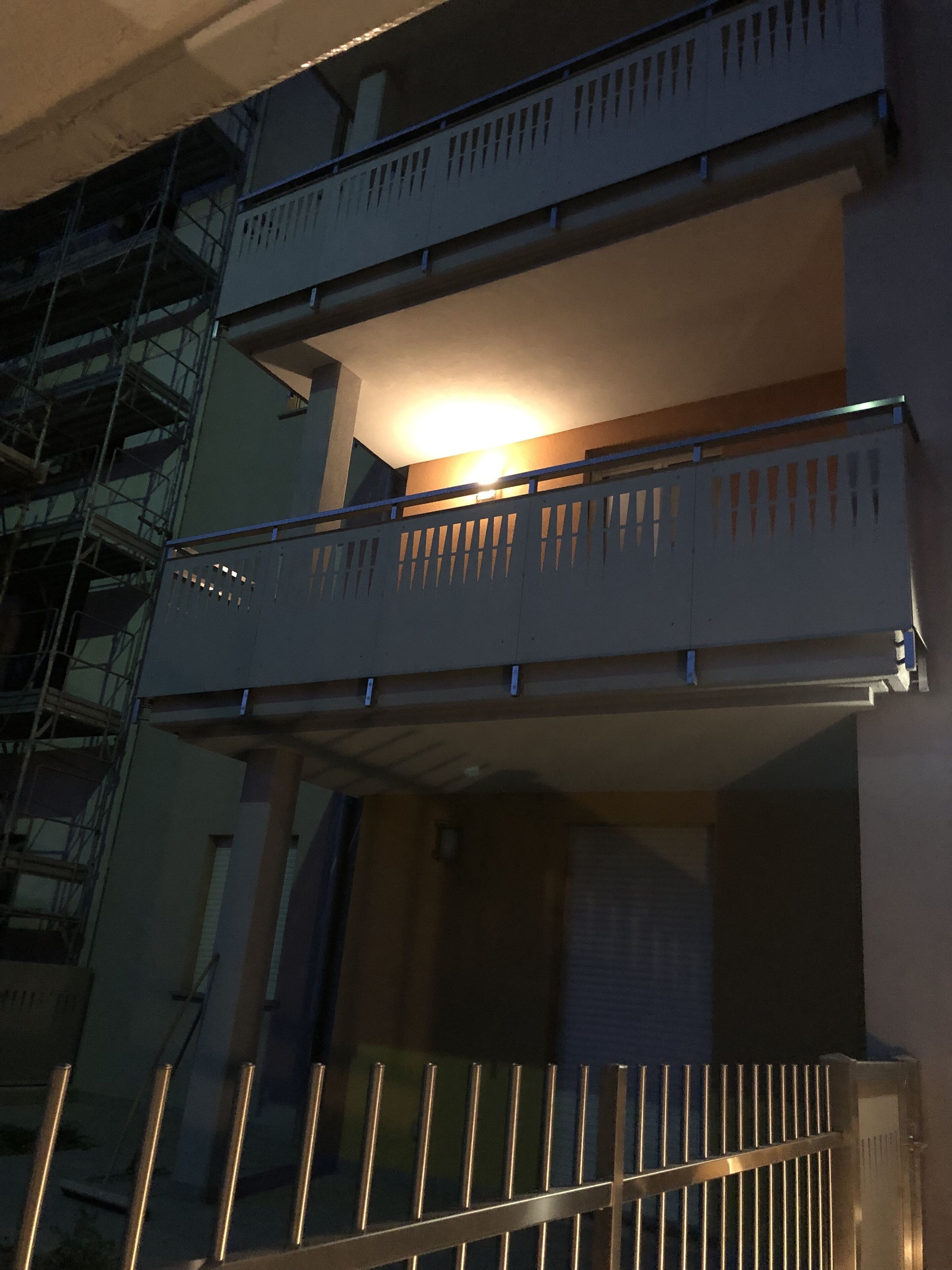 Un edificio de varios pisos con un balcón en el segundo nivel.