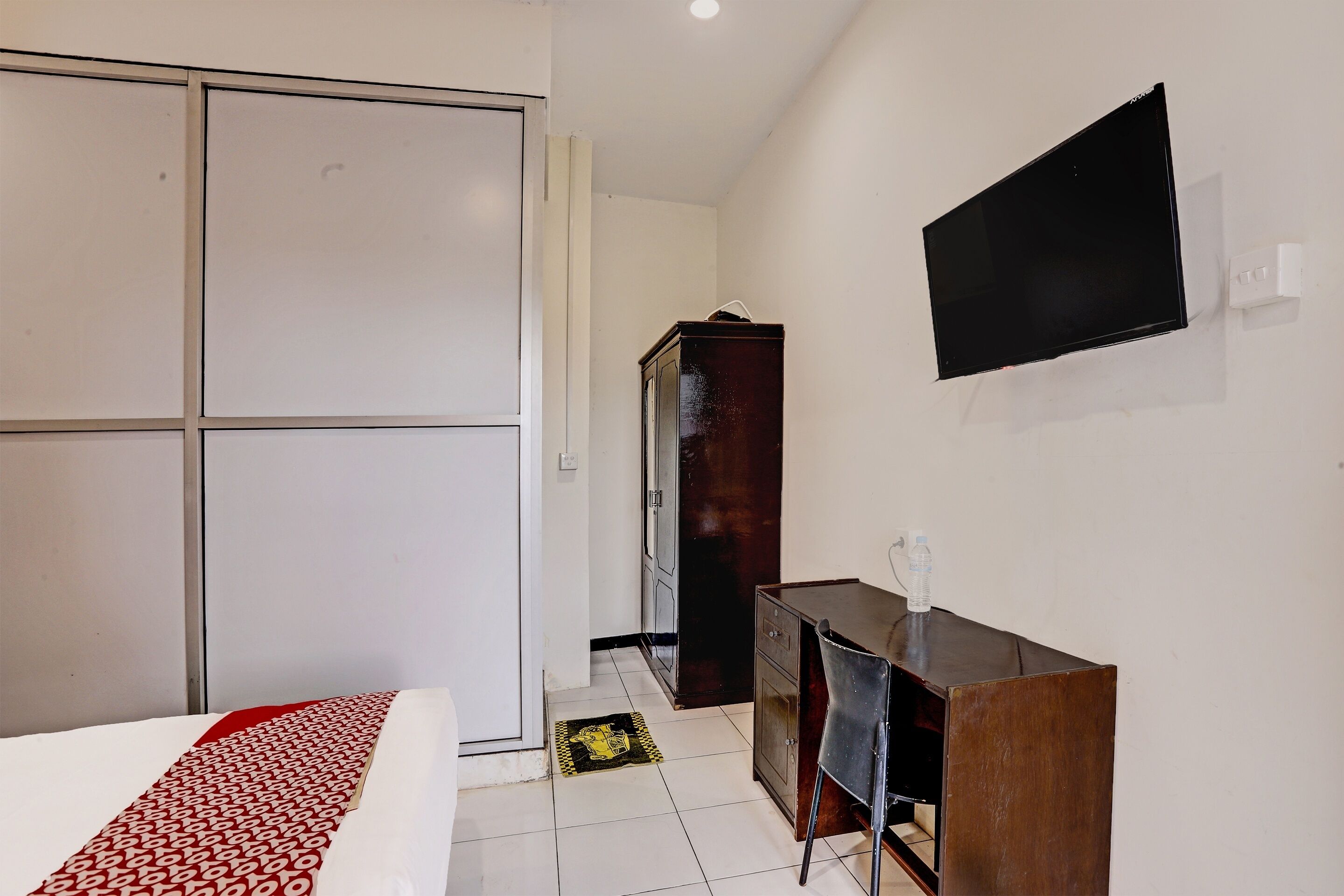 Une chambre à coucher comprenant un lit, une armoire, un bureau et un téléviseur.