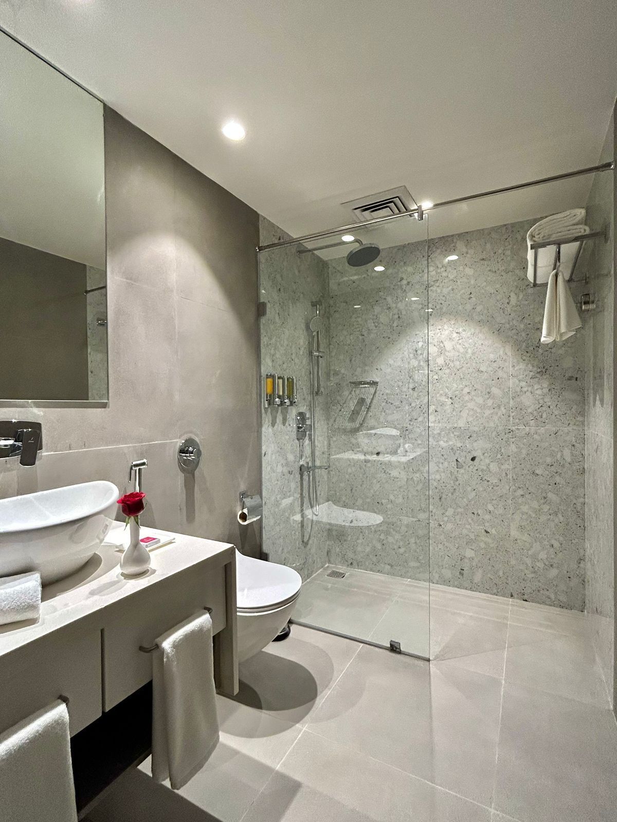 Un baño moderno con un lavamanos grande, inodoro y zona de ducha con cerramiento de cristal.