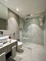 Un baño moderno con un lavamanos grande, inodoro y zona de ducha con cerramiento de cristal.