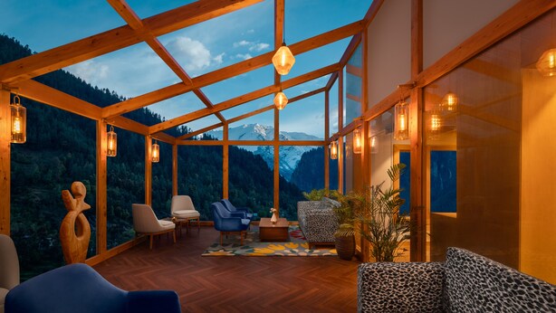Une pièce spacieuse avec un plancher en bois, un canapé, des fauteuils et une vue sur les montagnes.