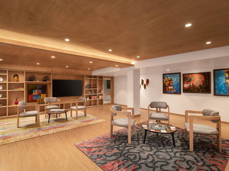 A spacious living room with wooden flooring, a large flat-screen TV, and a variety of decorative items and artwork on the walls.