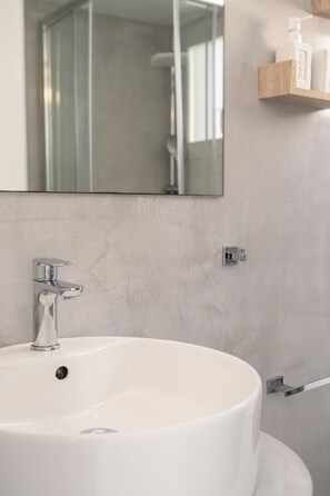 Un baño con lavamanos blanco, grifo cromado y espejo superior.