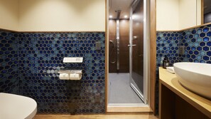 Een badkamer met douche, toilet en wastafel.
