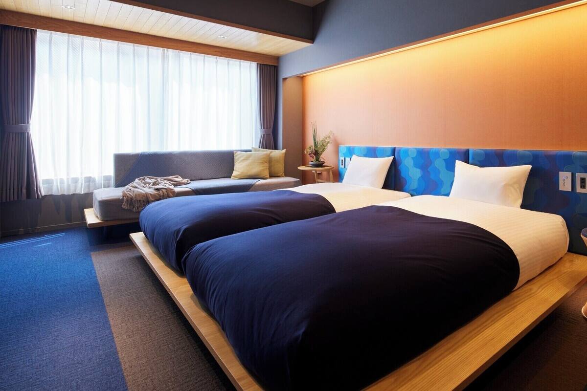 Een moderne hotelkamer met een groot bed, een bank en een kleine tafel met een plant.
