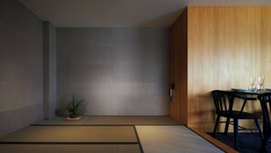 A minimalist dining area with a wooden panel wall, a small potted plant, and a table set for two with black chairs. - Minn Nijo-jo (Kyoto)