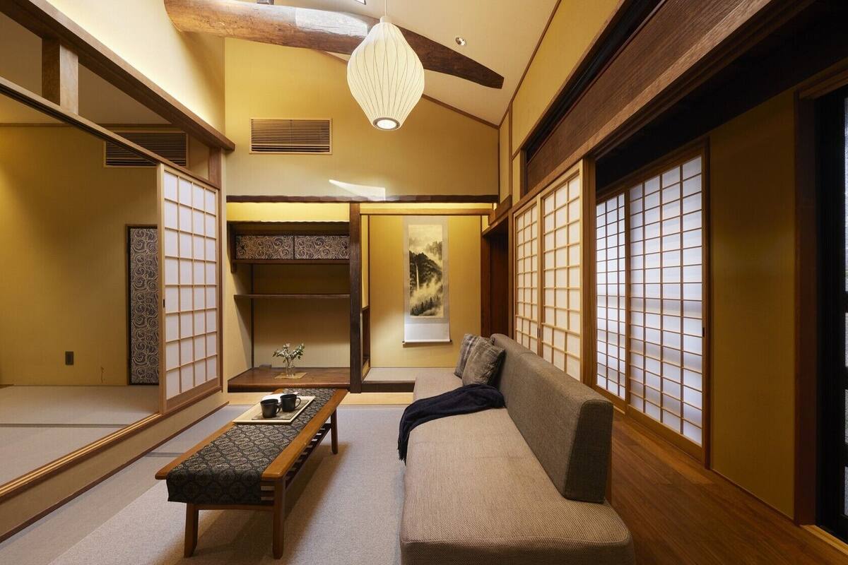 Een traditionele Japanse kamer met tatami vloerbedekking, een lage tafel, een bank en schuifdeuren.
