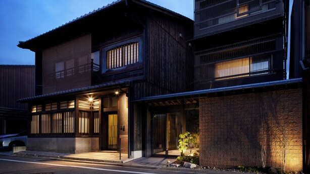 A traditional Japanese-style building with a wooden facade, large sliding doors, and a small garden area with a tree. - Minn Nijo-jo (Kyoto)