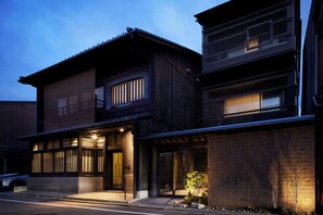 Il s’agit d’un bâtiment de style japonais traditionnel, doté d’une façade en bois, de grandes portes coulissantes et d’un petit jardin agrémenté d’un arbre.