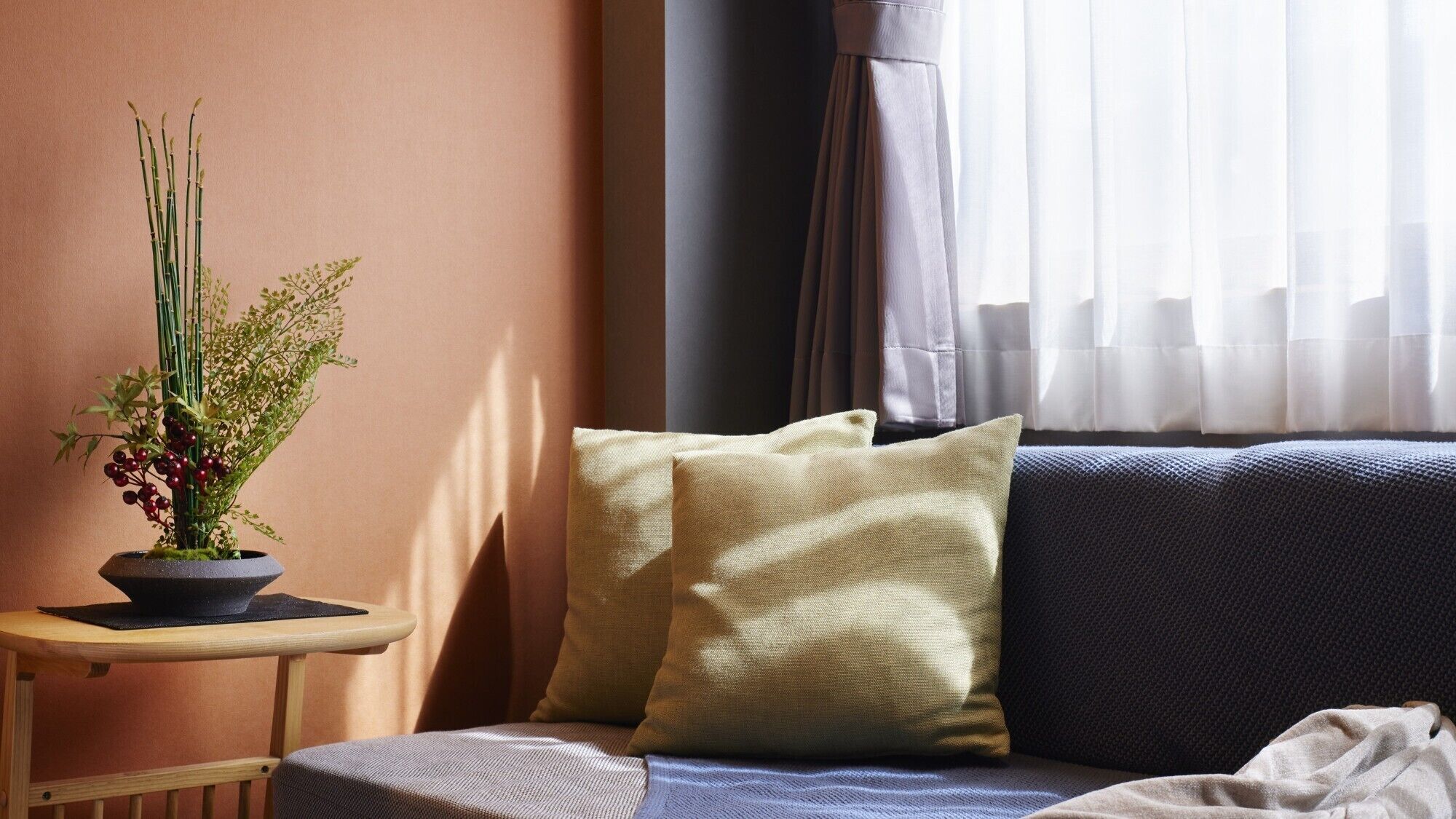 A cozy room with a sofa, a small side table, and a potted plant.