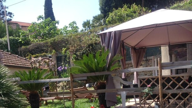 A garden with a hammock, pink roses, and a wooden pergola. - The Sea Flower (Sanremo)